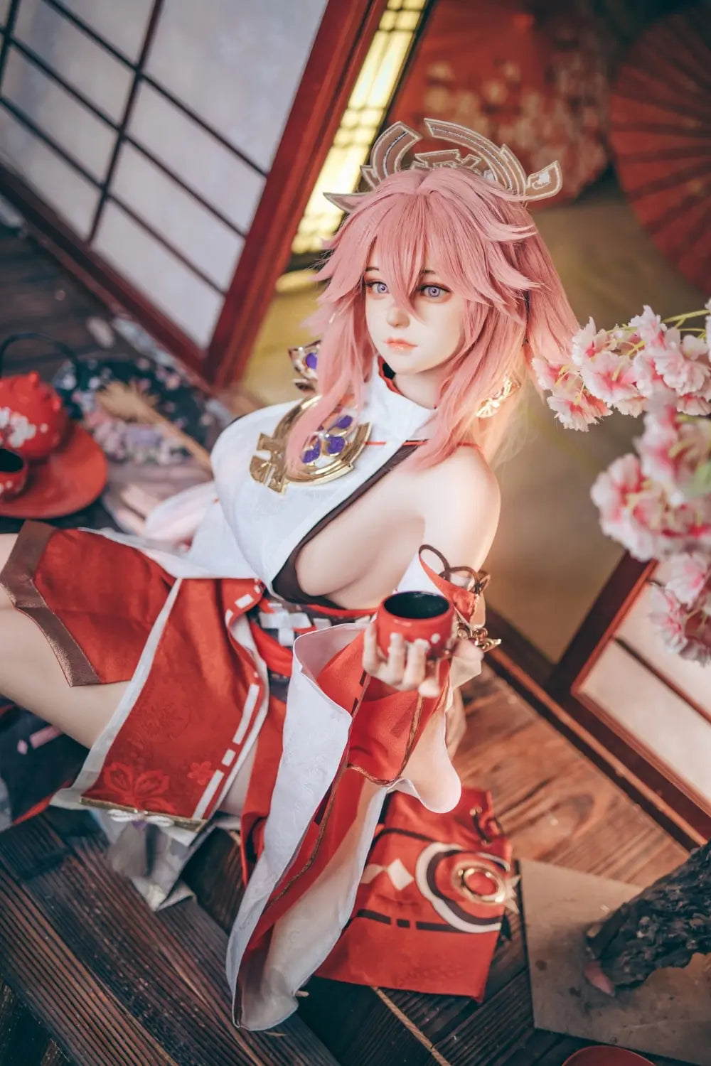  Yae Miko Genshin Impact cosplay sex doll, pink hair, sensual miko outfit, tatami room red cup – anime cosplay sex doll by TopLoveDoll,  red bell anklet, wooden geta sandals, Genshin Impact sex doll, sitting on the floor, holding a J-style red cup, high-angle bust shot