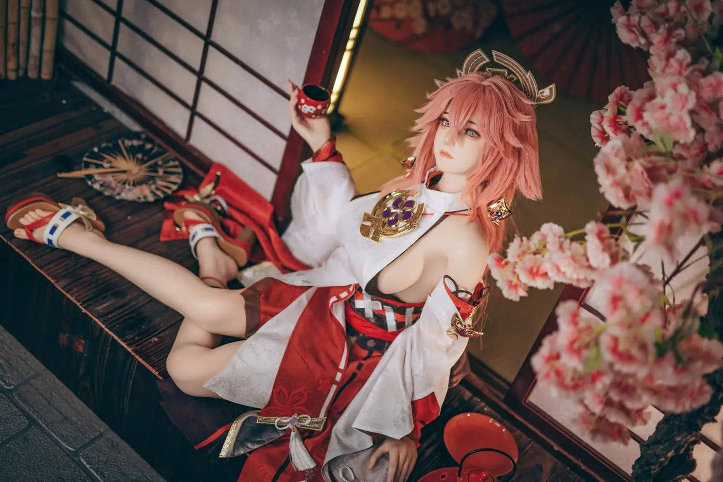  Yae Miko Genshin Impact cosplay sex doll, pink hair, sensual miko outfit, tatami room red cup – anime cosplay lifesize doll by TopLoveDoll,  red bell anklet, wooden geta sandals, Genshin Impact sex doll, sitting on the stairs, legs crossed, holding a J-style red cup, high-angle full shot, horizontal profile
