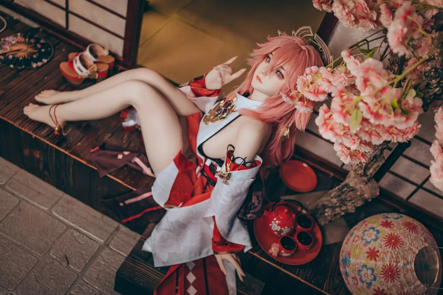  Yae Miko Genshin Impact cosplay sex doll, pink hair, sensual miko outfit, tatami room red cup – anime cosplay lifesize doll by TopLoveDoll,  red bell anklet, wooden geta sandals, Genshin Impact sex doll, sitting on the stairs, legs crossed, holding a J-style red cup, high-angle full shot, horizontal profile, doing a rock'n'roll gesture