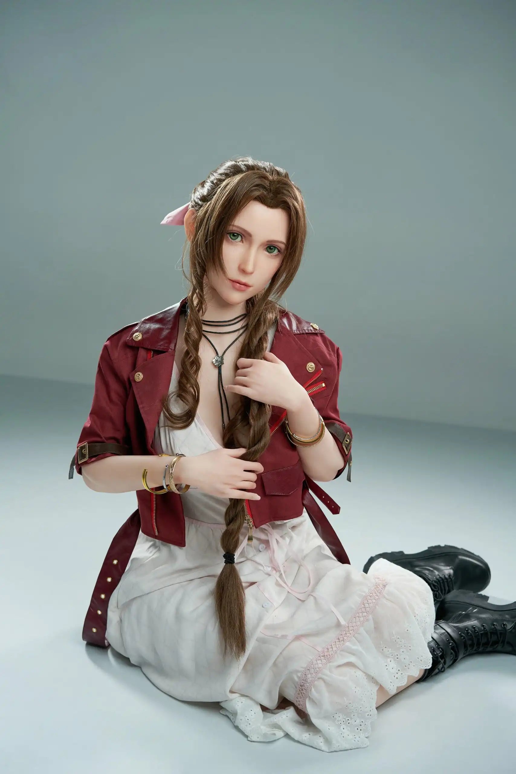 Seyo, brown wavy twin braids, pink hair bow, burgundy leather jacket, white deep-V slip dress, black leather mid-calf boots, green eyes, layered leather string choker, sit sideways on the floor, grey studio background – Tifa Lockhart cosplay sex doll by TopLoveDoll