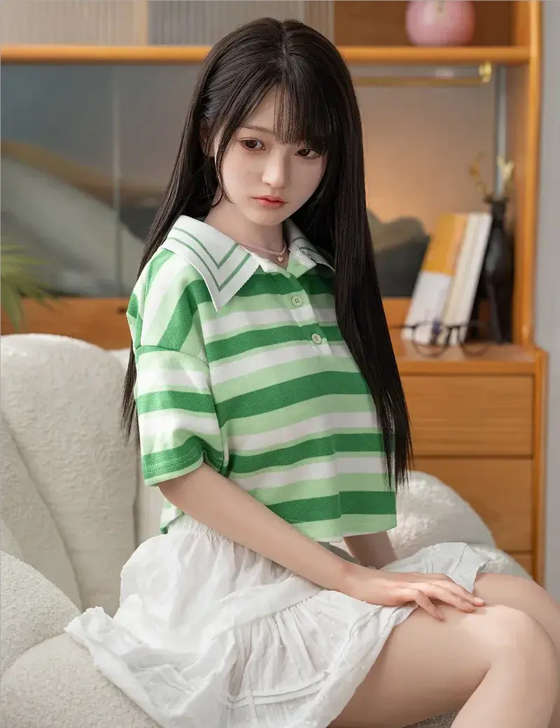 June, green stripe polo, white pleated skirt, brown Mary Jane leather shoes, white socks, petite and exquisite choker necklace, sitting in a couch and looking away, being shy and refreshing, eye-level bust shot –asian girl next door sex doll by TopLoveDoll