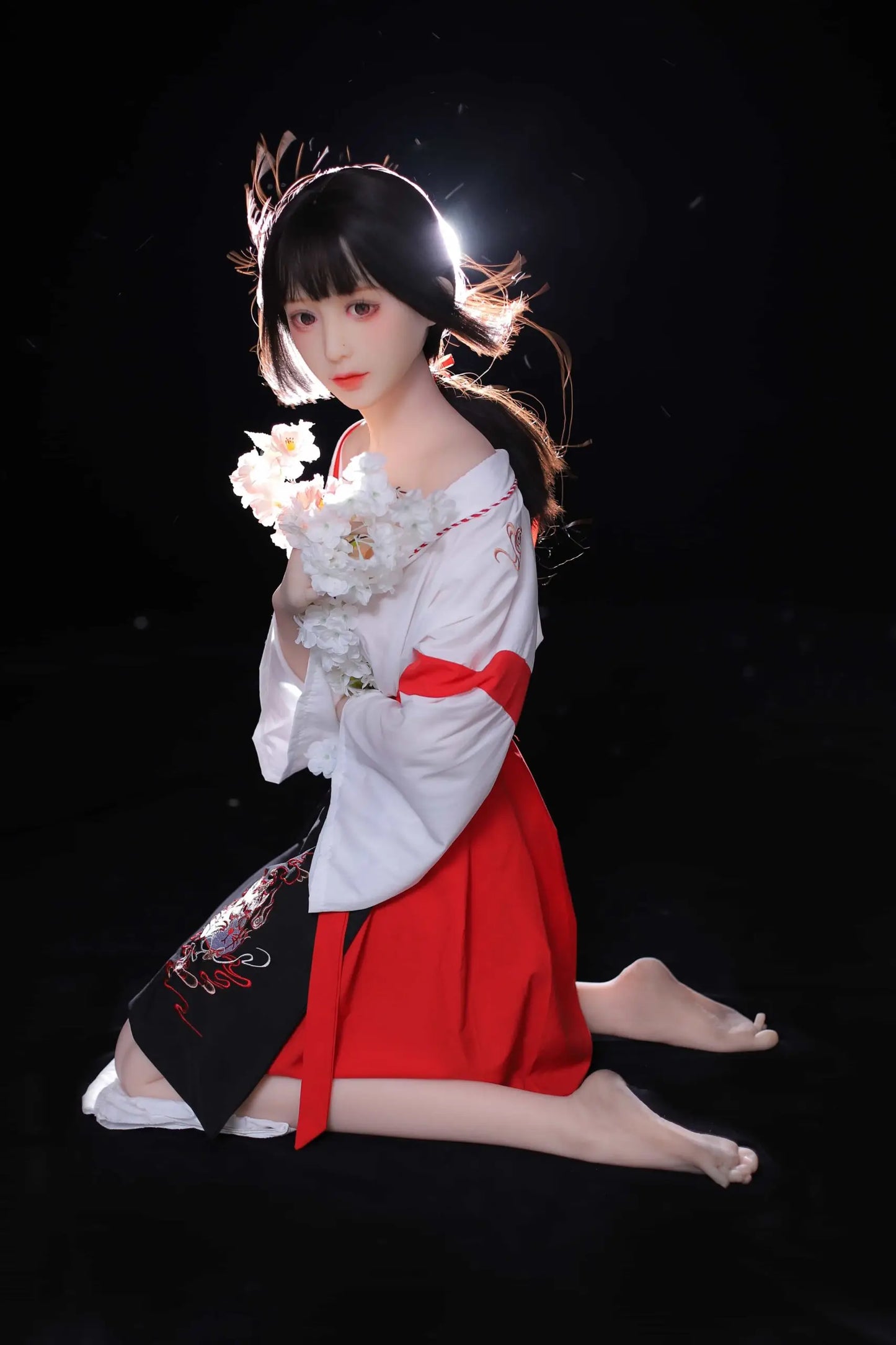Ethereal maiden, Aleena, black princess cut half-up hair, wind blowing up her hair, white miko top, red hakama floral folding fan, dark shrine backdrop, backlit shot, kneeling on the floor, holding some white flowers, looking at the camera – Japanese miko shrine maiden companion sex doll by TopLoveDoll