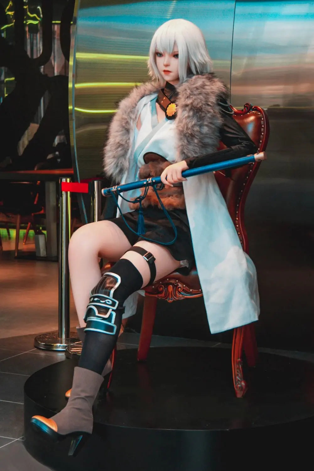 Alejandra, white short hair, teal leather combat armor, fur collar, leg bindings, Bai Yue Kui Ling Cage apocalypse queen, looking away, holding her weapon, sitting on a leather wooden sofa chair – Chinese anime cosplay fantasy sex doll by TopLoveDoll