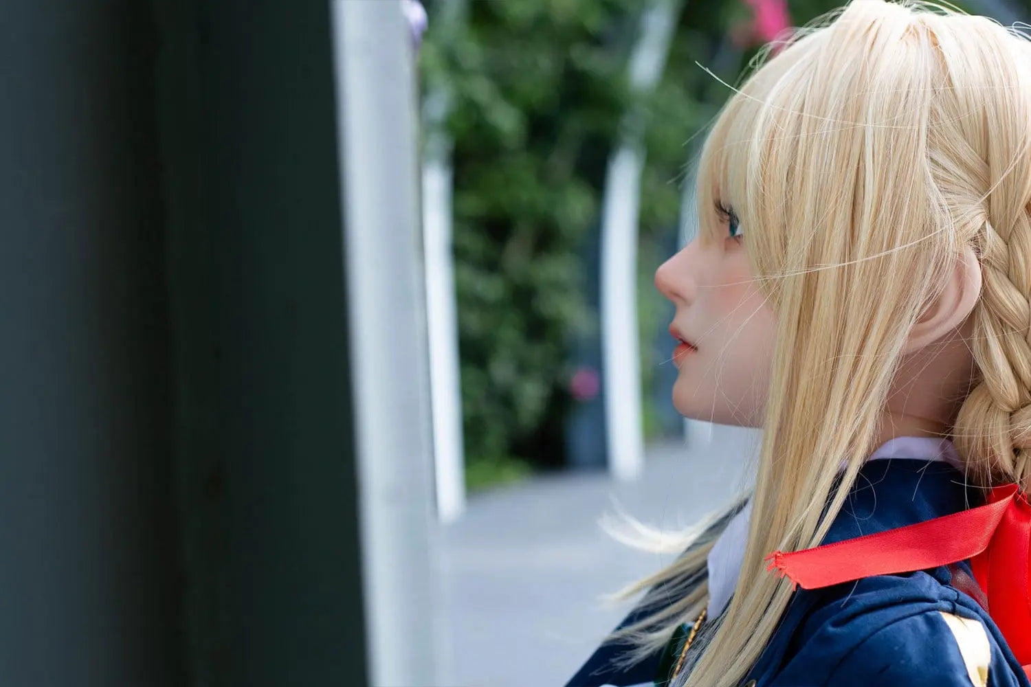 Aliana, golden straight long hair, blue eyes, navy Auto Memory Doll uniform, white apron, black leather boots, outdoor, brown gloves, holding a brown leather suitcase, eye-level shot, side face close up, look away, horizontal profile – Violet Evergarden cosplay anime sex doll by TopLoveDoll
