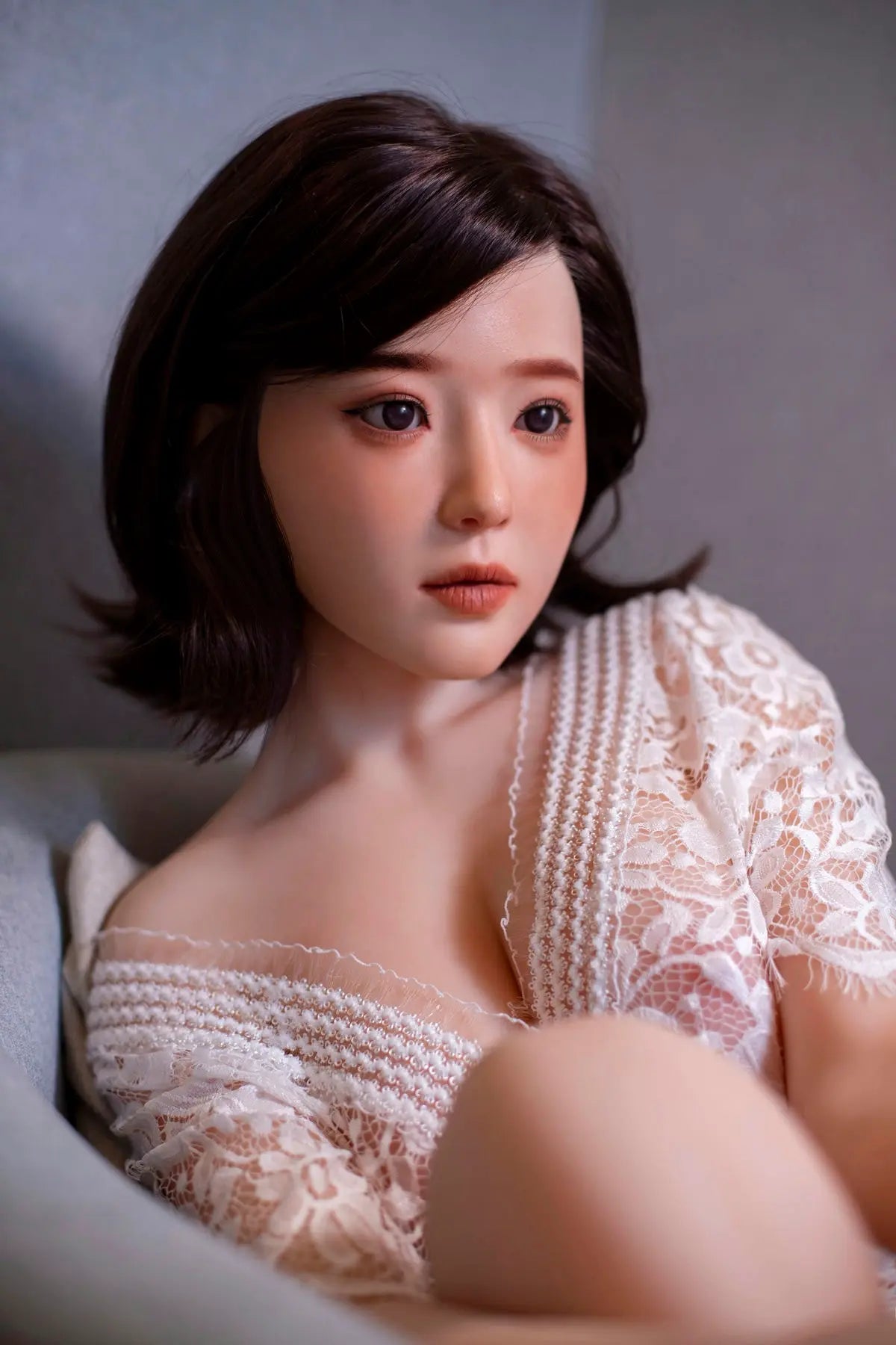 Aliza short dark bob, white lace dress, serene pose, indoor lighting, sitting in the couch, face close up perfectly combed hair– perfect wife Asian companion sex doll by TopLoveDoll