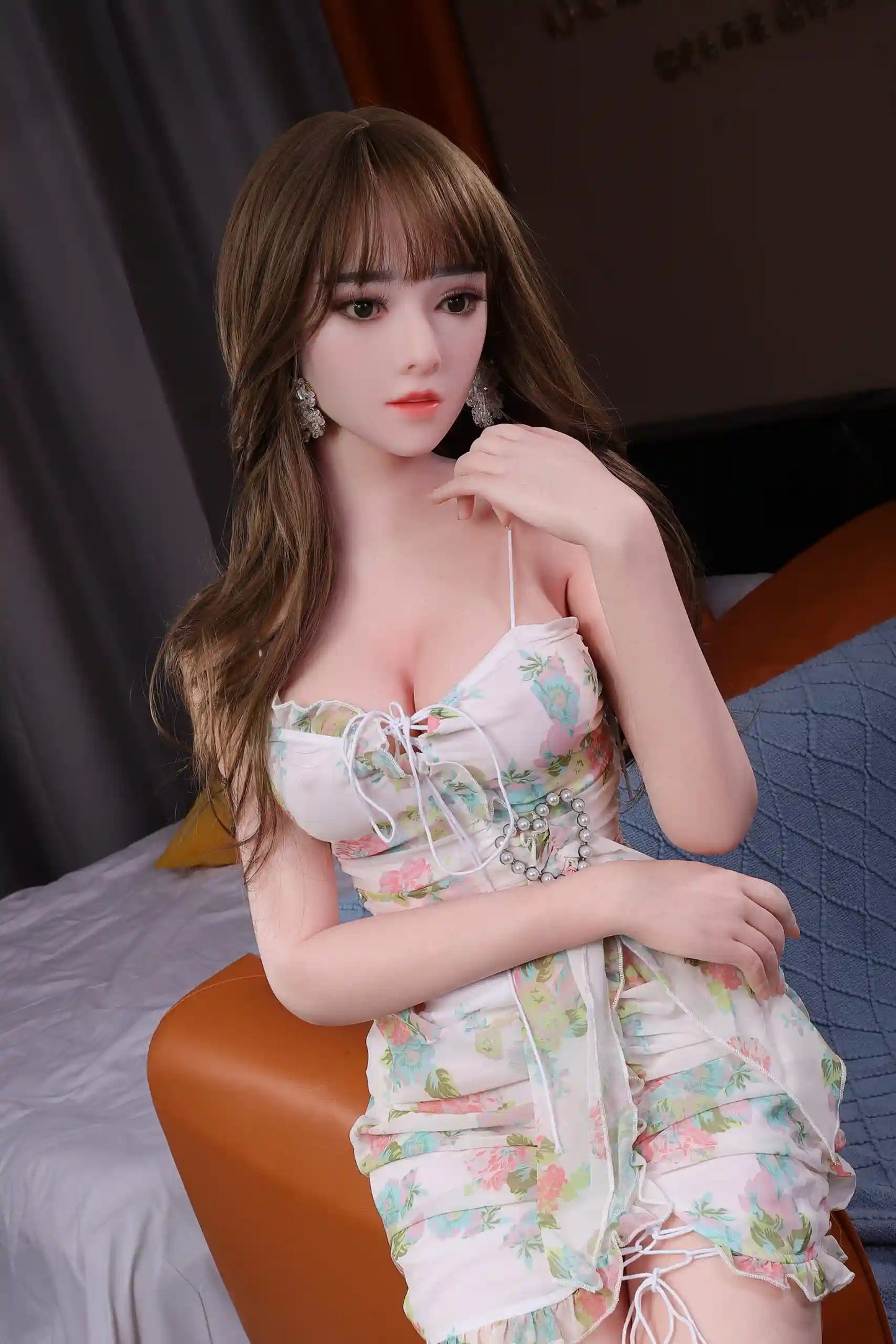 Amalia sweet Asian girlfriend brown wavy hair blunt bangs white floral spaghetti-strap dress sitting bed edge soft feminine expression, bust shot – girl-next-door companion sex doll by TopLoveDoll