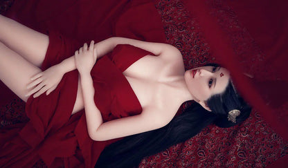 Amara cloud bun updo dark crimson gown red drape backdrop imperial reclining pose Chinese ghost beauty allure, lying on bed, showing her legs, shoulders, and cleavage – Asian fantasy companion sex doll by TopLoveDoll