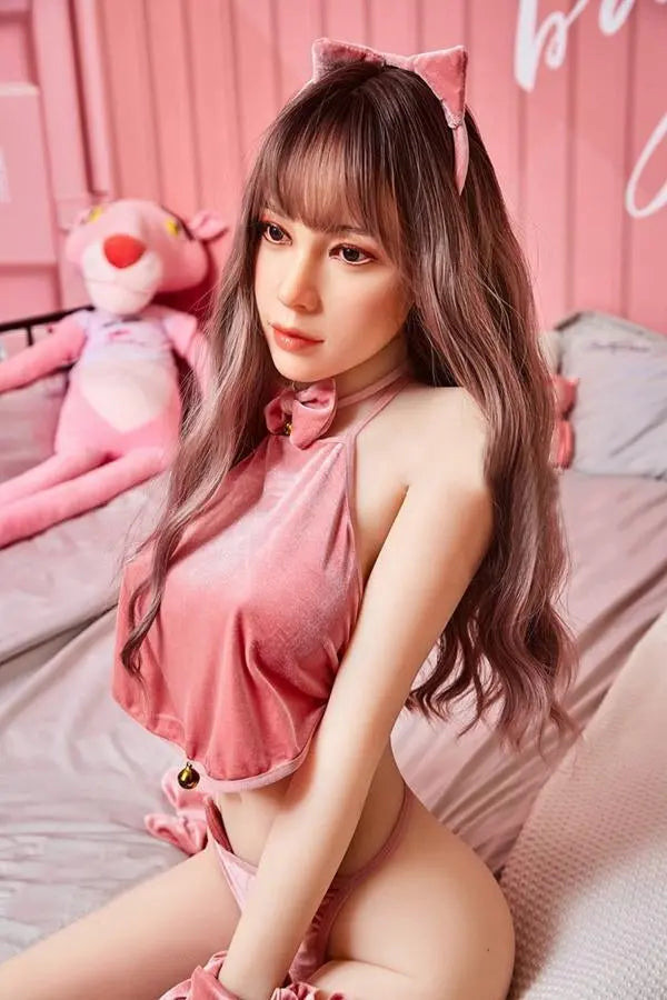 Amelia long wavy brown hair pink crop top pink mini skirt Y2K sweetgirl sitting in pink room soft Asian companion, sitting on a pink chair wearing pink lingerie set, sitting on bed, side view– girl-next-door sex doll by TopLoveDoll