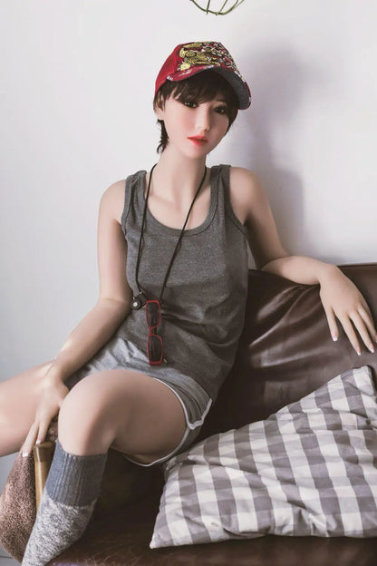 Amira short dark brown hair red lip grey tank denim shorts tomboy feminine, sitting on the arm of the chair, baseball hat, red sunglasses on the neck lace,– girl-next-door companion sex doll by TopLoveDoll
