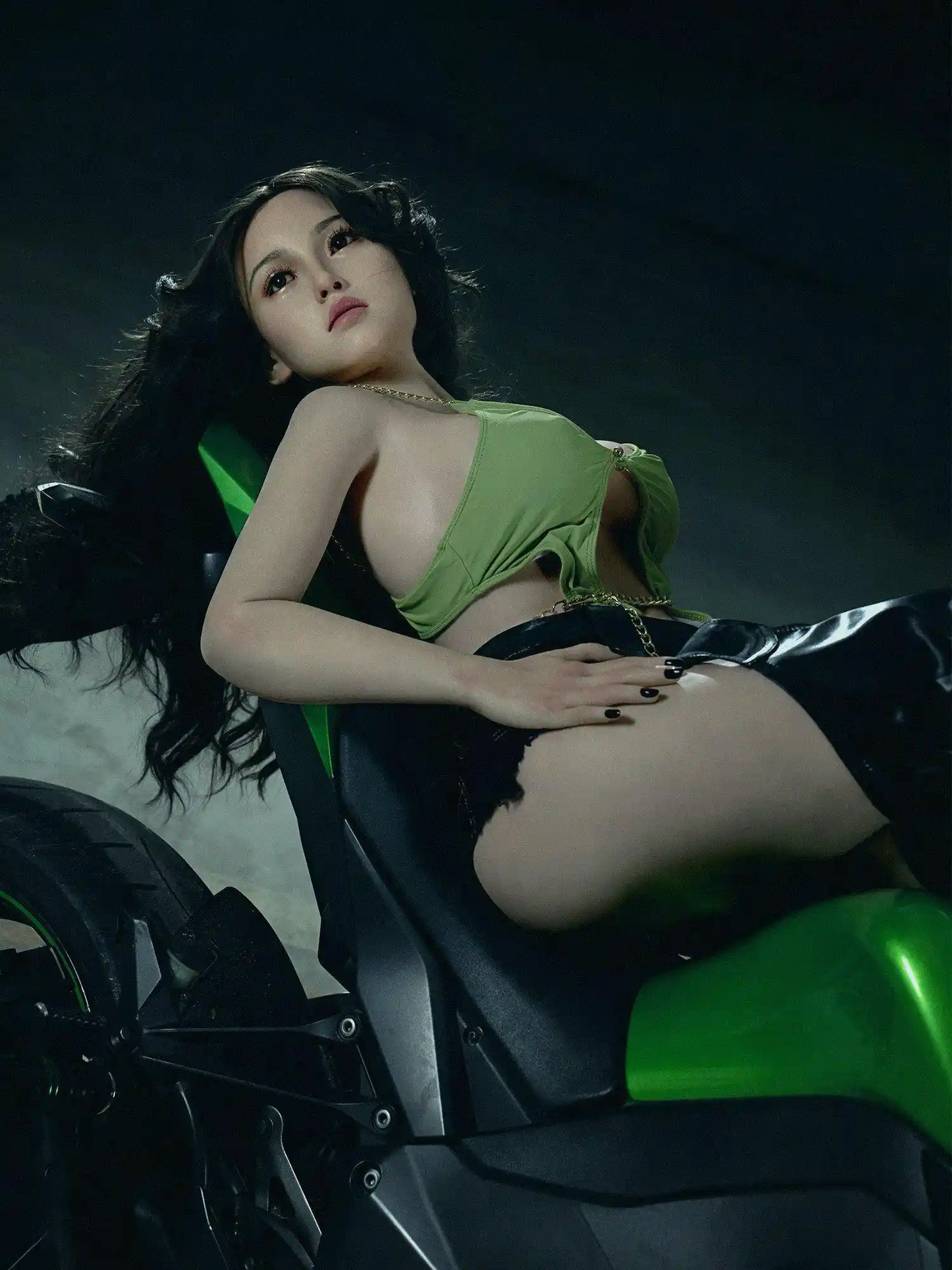 Armani biker girl Korean beauty sex doll, lying backwards on the muscle bike, exposing her great curves - green cutout top thigh-high leather boots soft face tough energy by TopLoveDoll