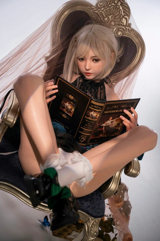 Addison sex doll serene composed downcast reading gaze, warm brown eyes, platinum blonde short bob with blunt fringe and gold ornate hair clip, coral lips, small gold stud earring, teal peacock blue velvet structured jacket with black lace high-neck inner blouse and ribbon tie detail, both legs raised and crossed with white lace-trim ankle socks and black Mary Jane heels with green bow detail, both hands holding ornate black hardcover book titled "Mother Of", seated on ornate gold baroque throne armchair wi